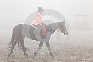 Girl riding horse on the field in the mist morning