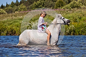Girl riding a horse in a river