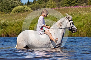 Girl riding a horse in a river