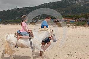 A girl riding a horse with a trainer