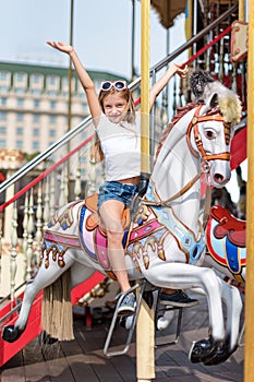 Girl riding on a merry go round. Little girl playing on carousel, summer fun, happy childhood and vacation concept