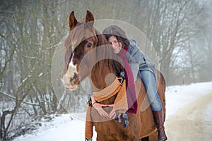 Girl riding red trakehner stallion horse with scarf in winter