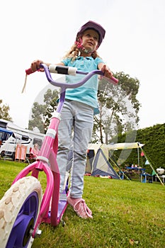 Girl Riding Scooter Whilst On Family Camping Holiday