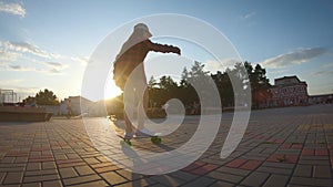 Girl riding on skateboard in motion of asphalt at sunset. Youth leisure concept. Active outdoor sport for kids.