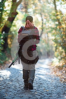 Girl with a rifle goes on the road in the woods.