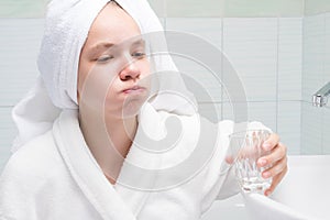 Girl rinses her mouth in the morning with clean water from a glass photo