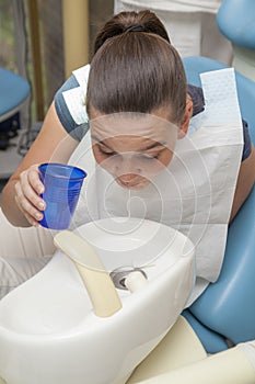 Girl rinsing mouth after dental inspection