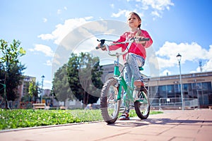 A girl in ripped jeans rides a bicycle in the park. Bottom view. Modern lifestyle