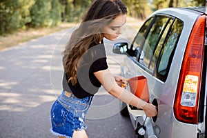 Girl on the road fueling car tank