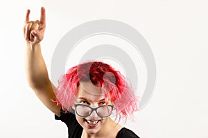 A girl rocker with red hair shows a hand gesture Heavy Metal HM on a white background. Concept of informal youth and