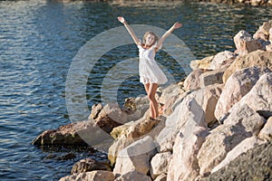 Girl on rocky seashore in sunny day