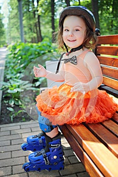 Girl in roller skates sits on bench and smiles at
