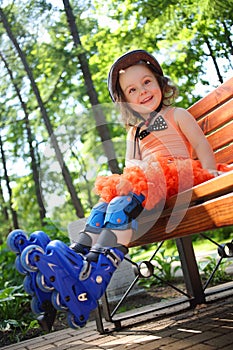 Girl in roller skates sits on bench and smiles in