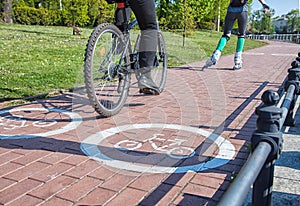 Girl roller-skating and bicycler on the bike path