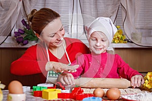 Girl rolling dough with her mother for bisquit photo