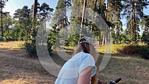 The girl rolls out and prepares the bike for a ride through the forest.