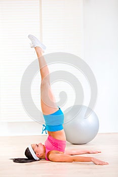 Girl at room practicing yoga pose with feet in air