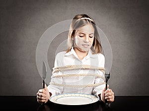 Girl roped sitting at table in front of a dish