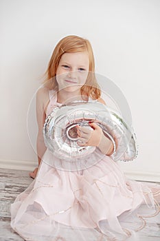 A girl in a rose dress on the floor