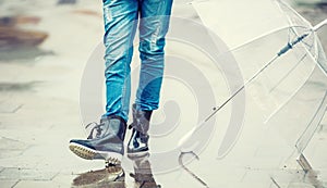 Girl in rubber boots with umbrella outdoors in rainy day