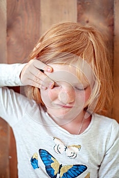 Girl rubs her eye with her hand