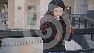 Girl rubs her hands because it is a cold urban image with a girl recharged with the sun in front