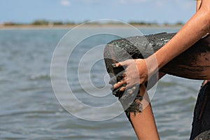 The girl rubs her leg with medicinal black mud from the lake.