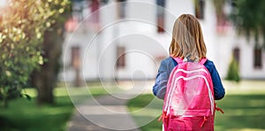 Girl with rucksack infront of a school building
