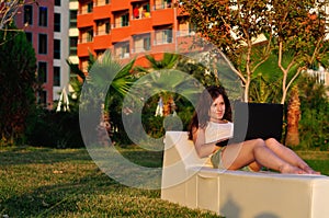 Girl on a rug with a laptop at sunset