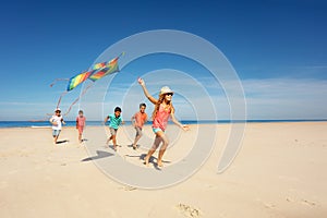 Girl run with kite and group of kids on the beach