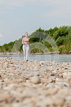 Girl runner running by riverbank . Healthy fitness woman jogging outdoors