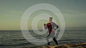 Girl runner training sandy beach evening time. Sporty woman running near ocean.