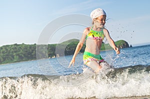 girl running beach shore splashing water in blue sea