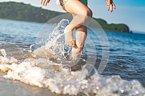 girl running beach shore splashing water in blue sea