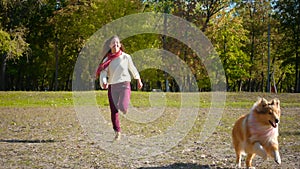 Girl running with collie dog at autumn park