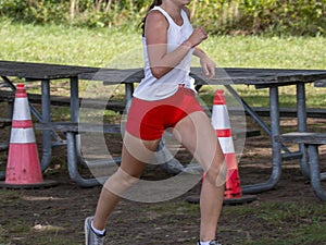 Girl running in a cross country race passing a picnic table