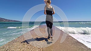 Girl running down the pier to the sea, jogs in the morning, slow motion hd video