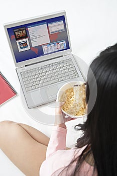 Girl running ebusiness on notebook computer while eating instant photo