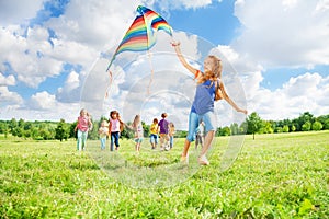 Girl running with kite with friends
