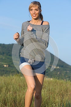 Girl running on meadow listening to music on a mp3