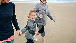 Girl running with two women on the beach