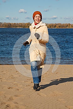 Girl runs along beach autumn day.