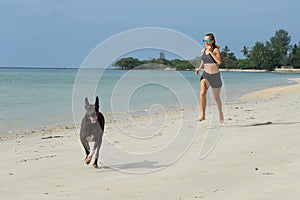 The girl runs on the beach, the sports girl, in hot weather at the sea, dressed in black shorts and an undershirt.