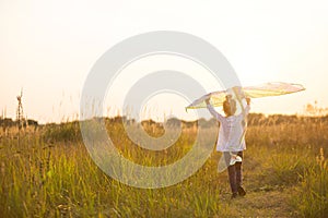 A girl runs into a field with a kite, learns to launch it. Outdoor entertainment in summer, nature and fresh air. Childhood,