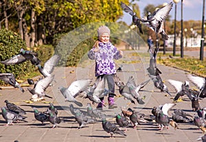 A girl runs to disperse pigeons