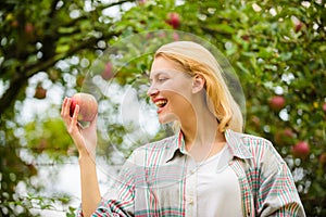 Girl rustic style gather harvest garden autumn day. Farmer pretty blonde with appetite red apple. Woman hold apple