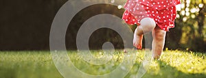 Girl`s bare feet in the green grass. little Happy child running at sunset barefoot outdoor