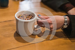 Girl`s hand holding a cup of teacup of rose petals and red berries