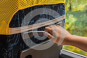 The girl`s hand is holding on to the rubber handle of the seat on the bus, close-up