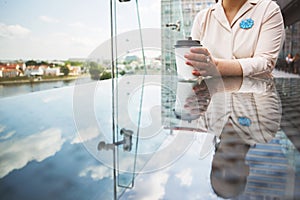 Girl`s hand holds a cup of coffee. the girl is sitting in a cafe